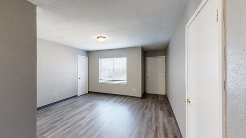 the living room of an apartment with wood flooring and a window